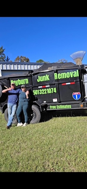 Rayburn Junk Removal crew smiling in front of the branded trailer on a sunny day